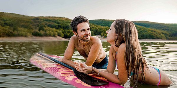 Junge Frau und Junger Mann auf Stand up Paddle im Wasser