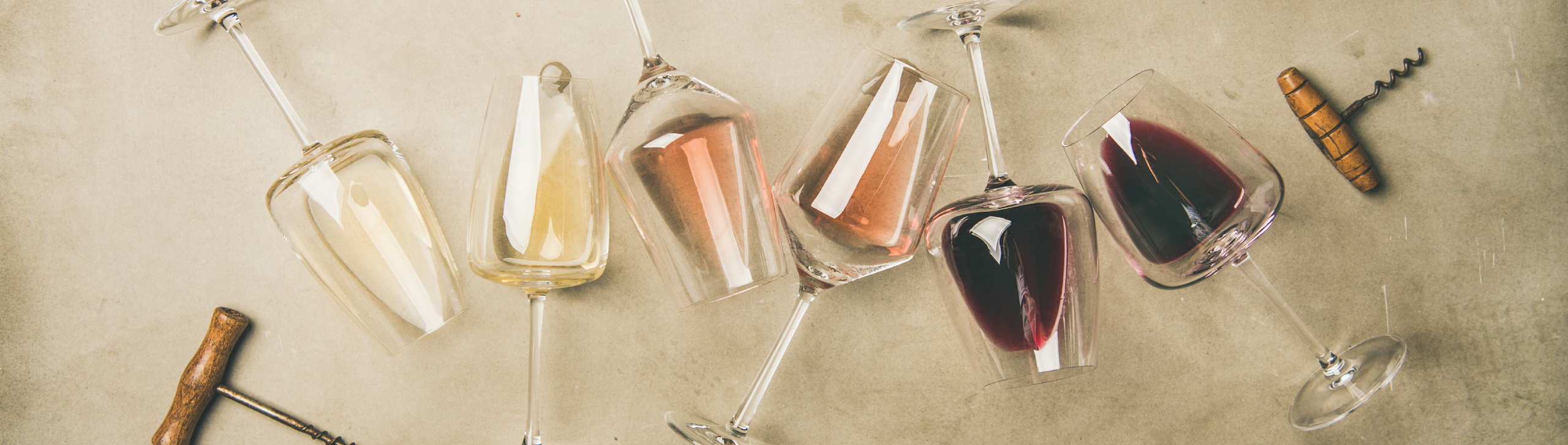 Liegende Weingläser, die mit einem Schluck Rot-, Rosé- und Weißwein gefüllt sind.