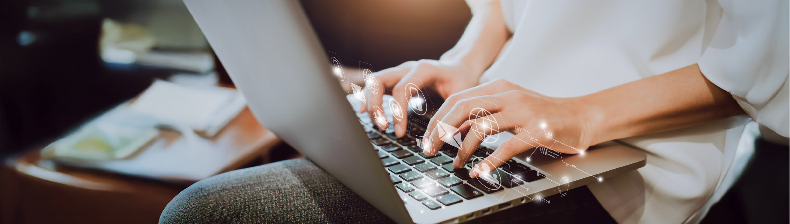 Nahaufnahme eins Laptops, an dem gearbeitet wird. E-Mail und Internetsymbole verstärken die Aussage des Bildes.