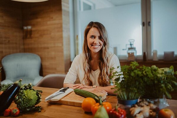 Foto unserer Ernährungsexpertin Silke Salay an einem Tisch mit frischem Gemüse.