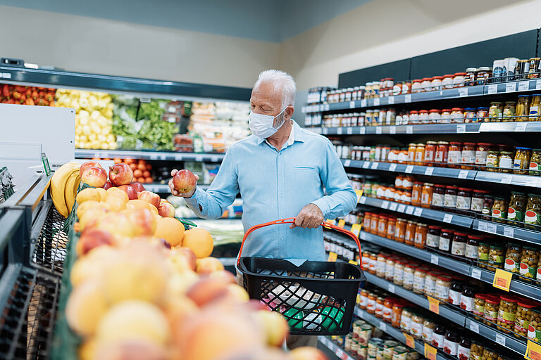 Älterer Mann mit Maske beim Einkaufen im Supermart.