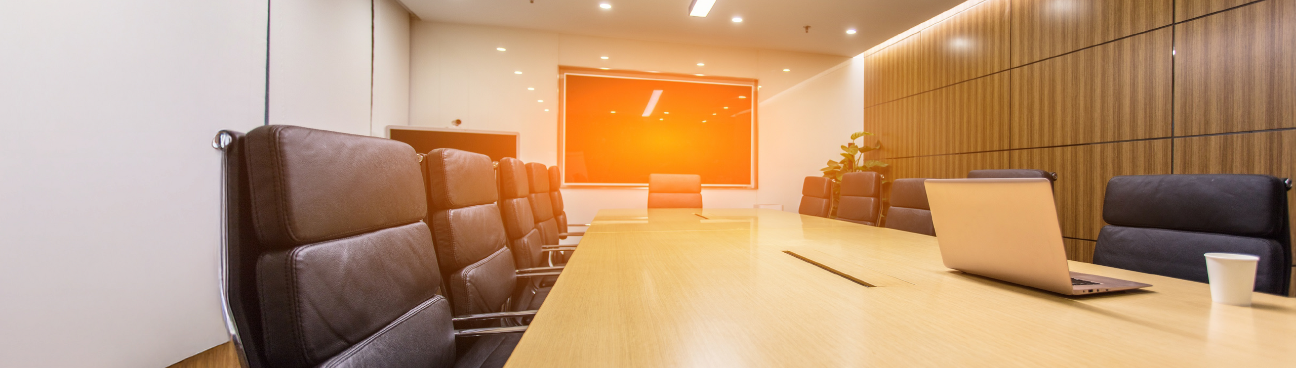 Konferenzraum mit einem großen Tisch und Stühlen. Ein Laptop steht auf dem Tisch.