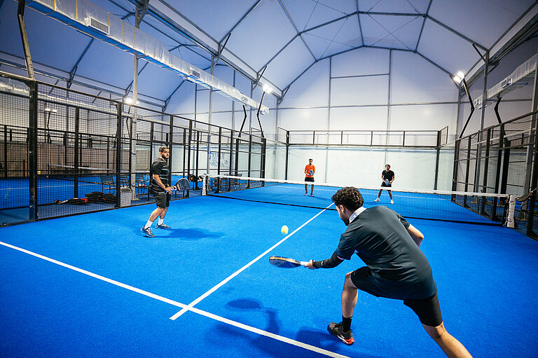 Vier Freunde spielen in einer Padel-Tennis-Halle Padel.