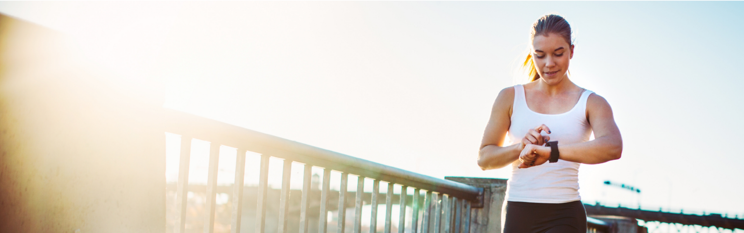 Junge sportliche Frau beim Joggen, schaut auf ihre Smartwatch.