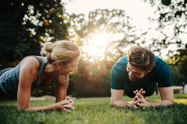 Mann und Frau beim Bodyweight-Training im Freien.