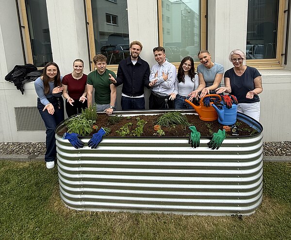Azubis präsentieren das frisch bepflanze Hochbeet.