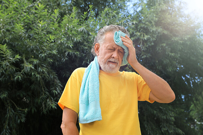 Älterer Herr, der erschöpft wirkt durch das heiße Wetter im Sommer.