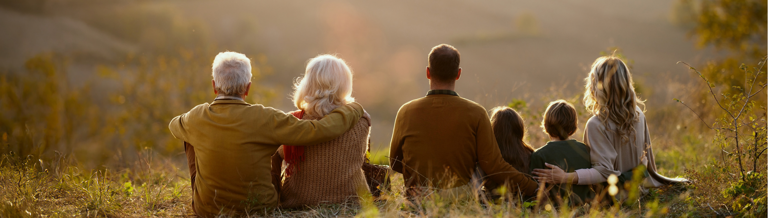 3 Generation sitzen auf einer Wiese und genießen die gemeinsame Zeit.