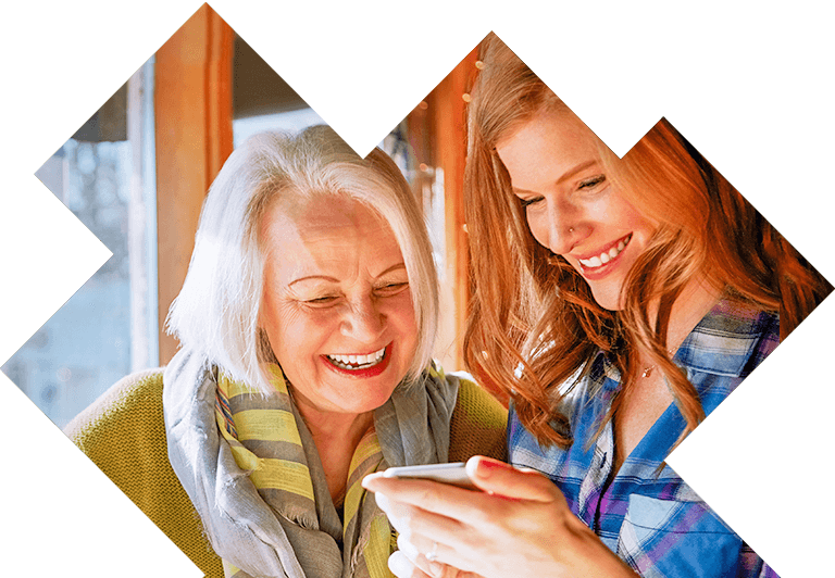 Ältere Dame und ihre Tochter schauen gemeinsam in ein Smartphone