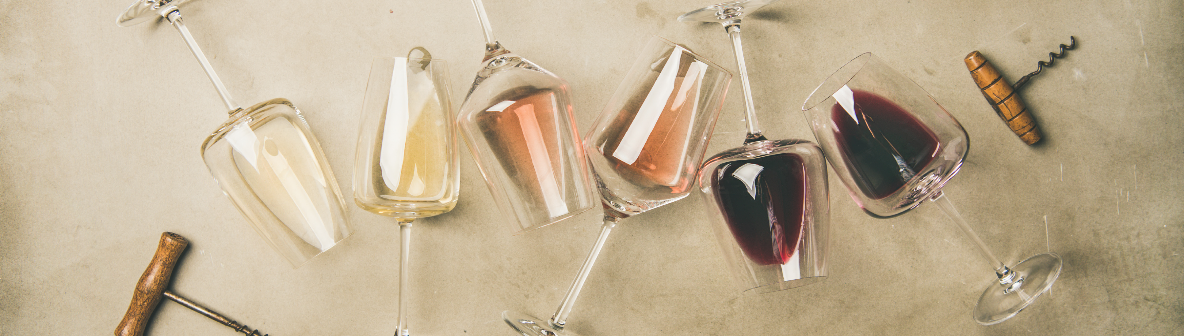 Liegende Weingläser, die mit einem Schluck Rot-, Rosé- und Weißwein gefüllt sind.