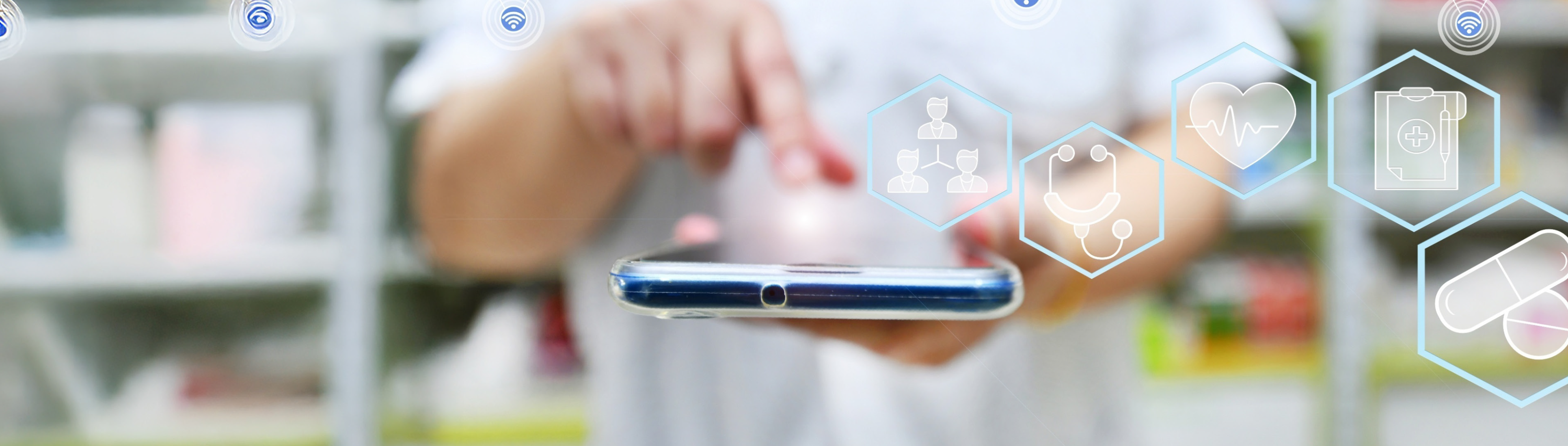 Verschwommener Hintergrund: Apotheker hält Smartphone in der Hand. Darüber sind Symbole aus dem Gesundheitswesen eingeblendet. 