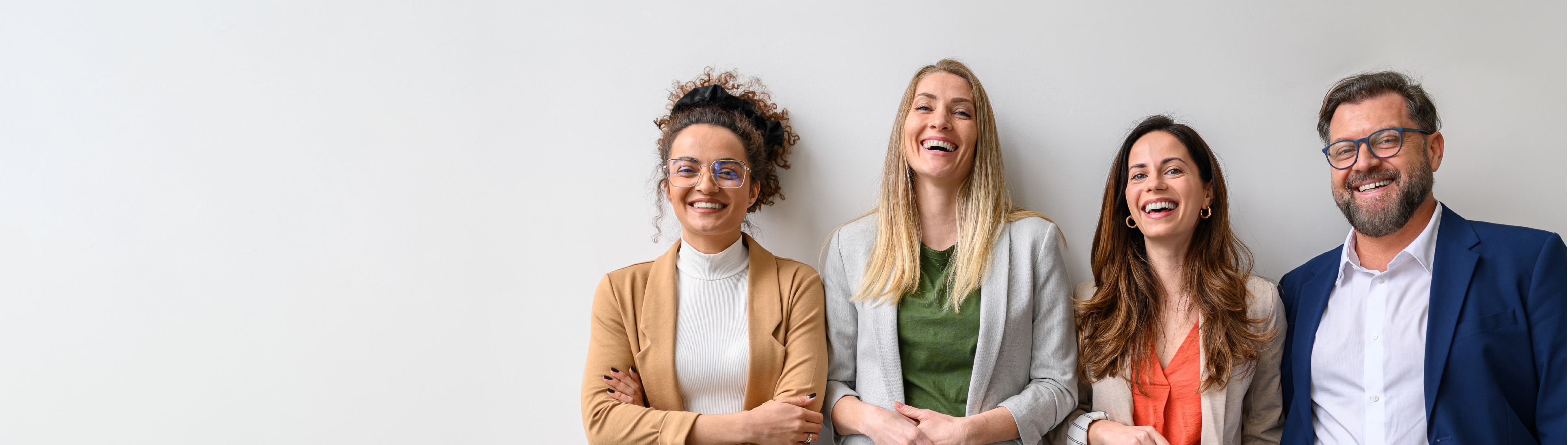 2 Frauen und ein Mann stehen in einer Reihe und lachen in die Kamera. 