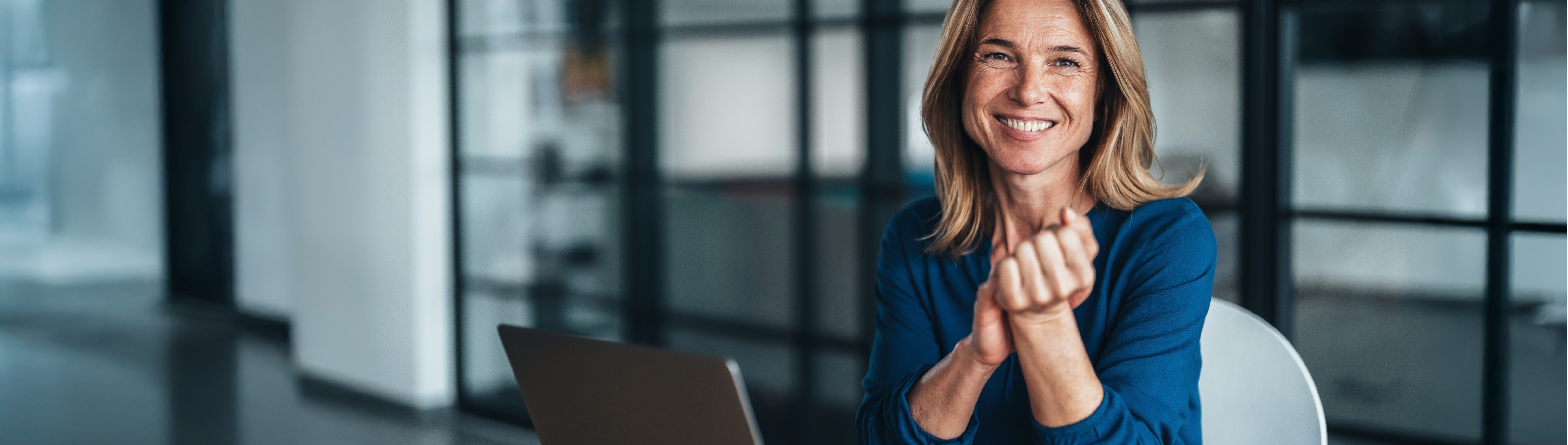 Business-Frau sitzt am Tisch mit einem Laptop vor sich. 