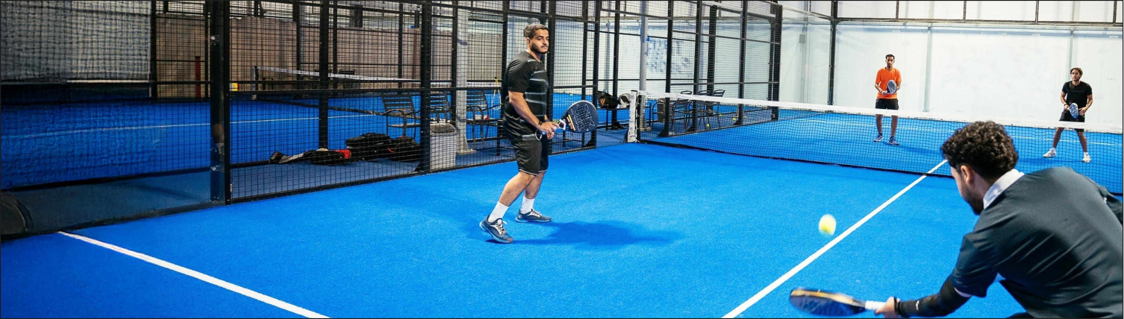 Vier Freunde spielen in einer Padel-Tennis-Halle Padel.