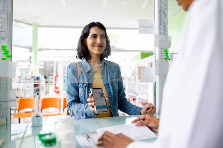 Frau zeigt in der Apotheke ihr E-Rezept